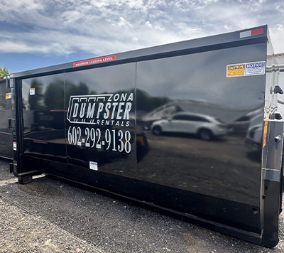 30 YARD DUMPSTER Black dumpster with "Zona Dumpster Rentals" logo and contact number 602-292-9138, parked in an outdoor area.